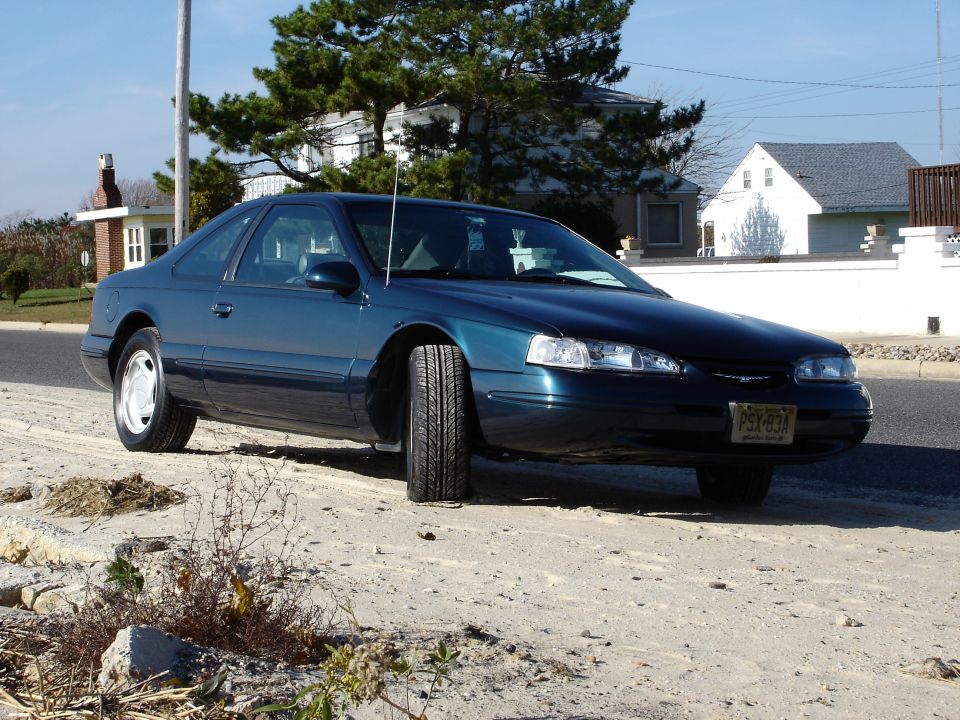 Teal 1996-97 Ford Thunderbird coupe parked roadside in a beach-town neighborhood