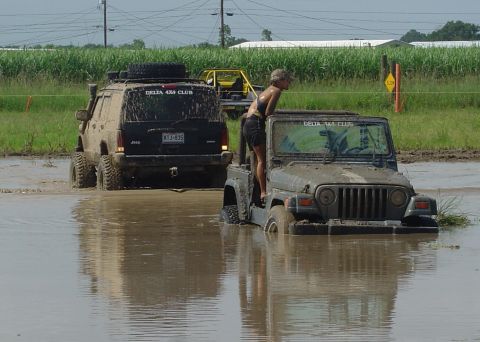 2000 Jeep Cherokee - Off-road vehicles navigate a muddy terrain, with one Jeep partially submerged in water.
