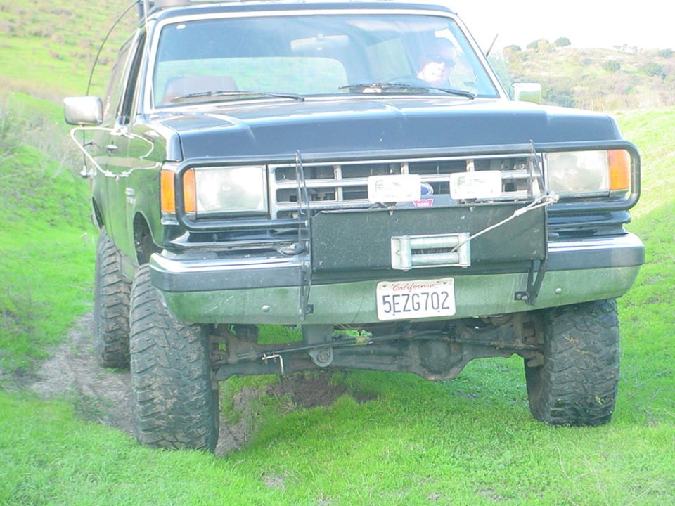 1987 Ford Bronco front view with winch and off-road tires on grassy terrain