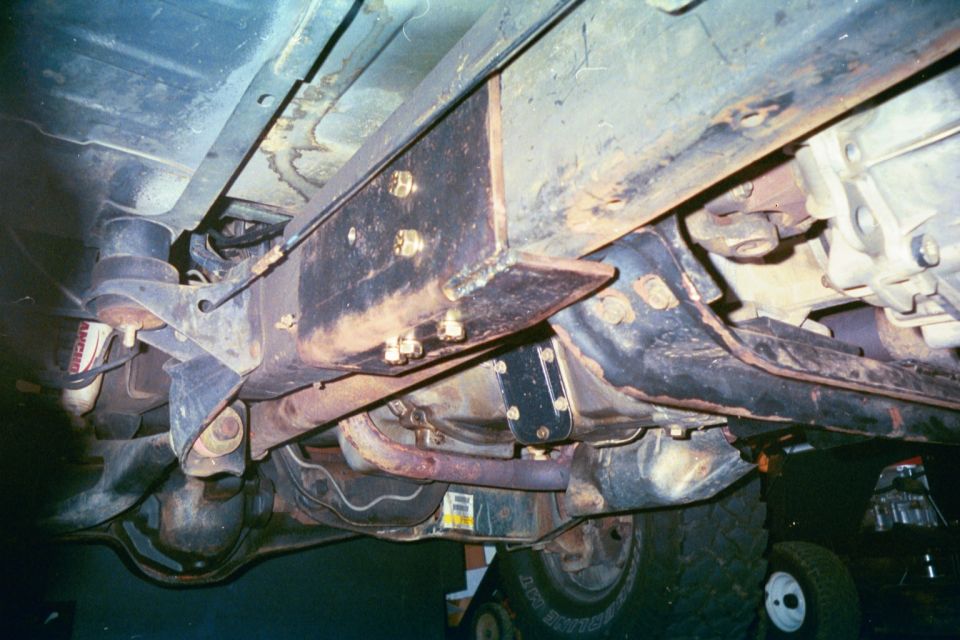 Rusty truck undercarriage showing frame, differential, and red Rancho shock
