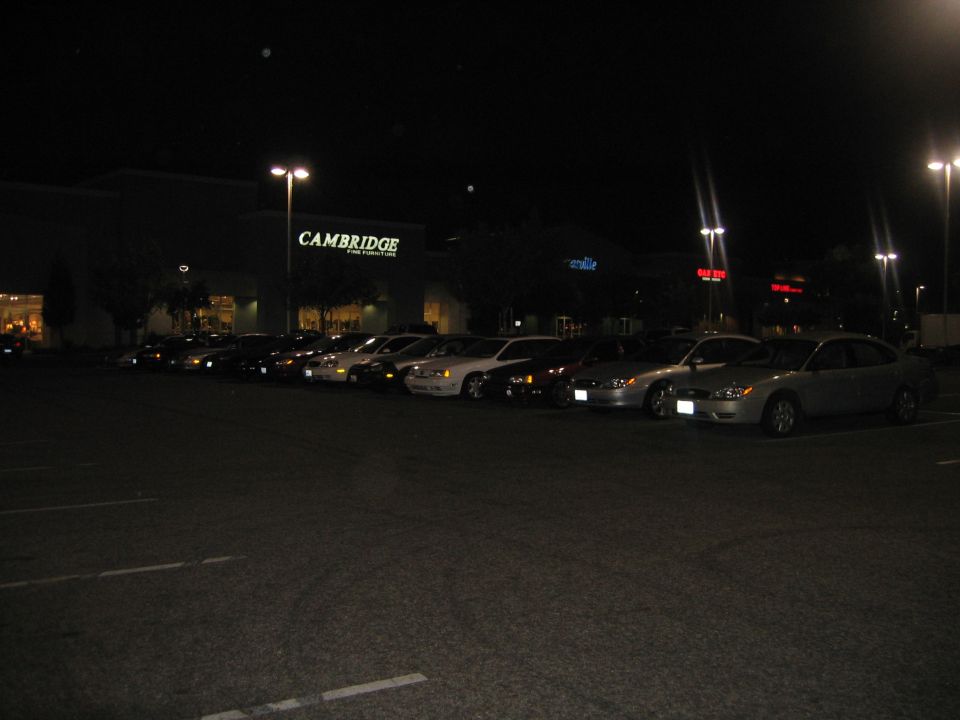 Cars parked in a lot at night in front of a Cambridge store