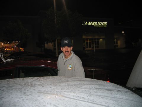 2002 Ford Taurus - A man stands in a parking lot at night, with a red car beside him and a furniture store behind.