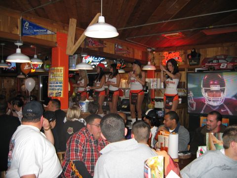 2002 Ford Taurus - A lively scene inside a Hooters restaurant, waitresses on a stage and patrons enjoying themselves.