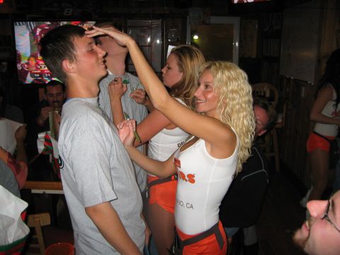 2002 Ford Taurus - A group of people are gathered in a bar, with two women in Hooters uniforms interacting with a man.