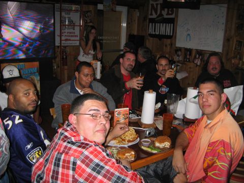 2002 Ford Taurus - Several men are gathered around a table, enjoying food and drinks in a casual setting.