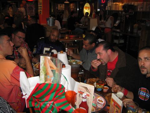 2002 Ford Taurus - Several men are seated at a table in a restaurant, eating food and talking.