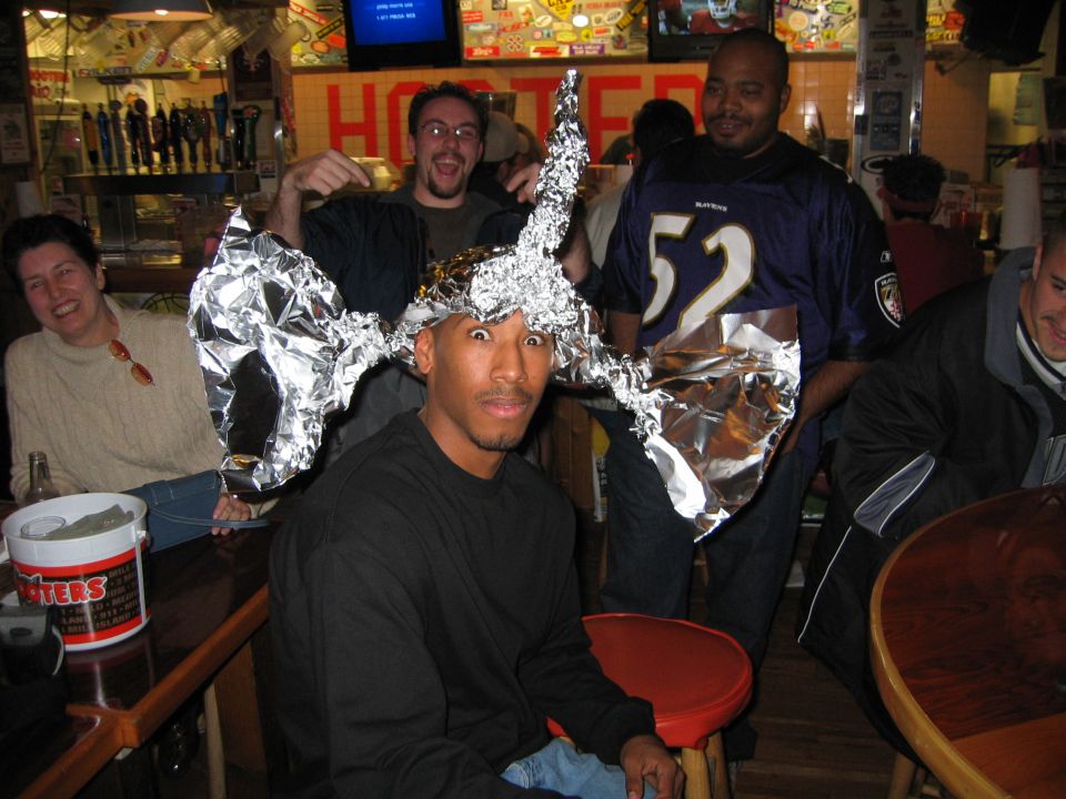 People wearing tinfoil hats in a bar, one man in a Ravens jersey