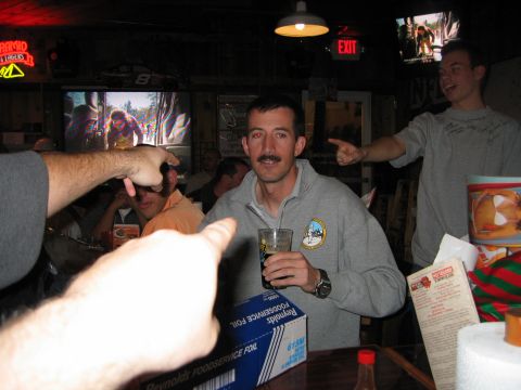 2002 Ford Taurus - People gathered in a bar, with multiple pointing fingers and screens displaying content.