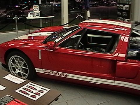 1991 Ford Taurus - A red Ford GT with white racing stripes is displayed indoors, with "FORD GT" text visible on its side.