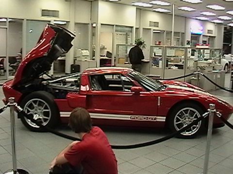 1991 Ford Taurus - A red Ford GT is displayed indoors with its front hood open, revealing the engine compartment.