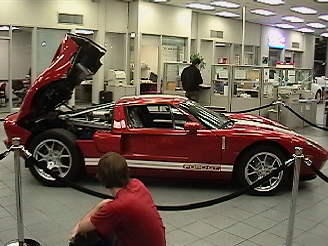 Red Ford GT with hood open, person sitting in front