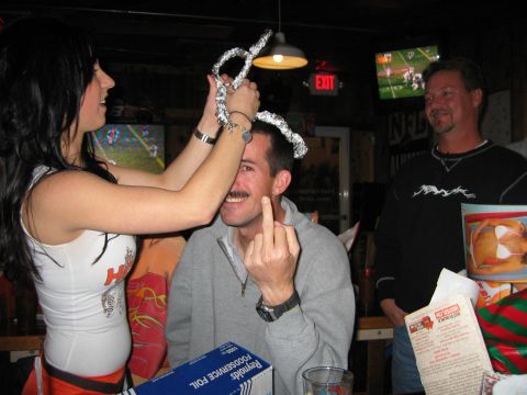 2002 Ford Taurus - A man is playfully given a foil crown while giving the middle finger in a bar setting.