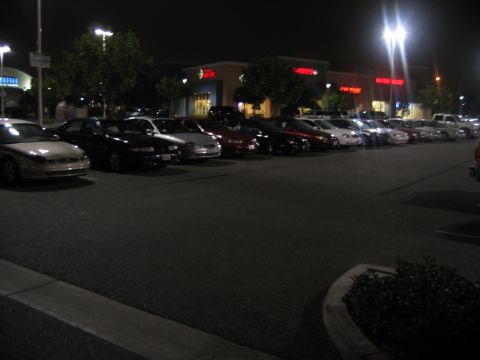2002 Ford Taurus - Cars parked in a lot at night in front of a strip mall with lights on.