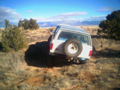 1987 Ford Bronco - This white SUV, likely from the 1980s, is seen off-road with a spare tire on its rear.