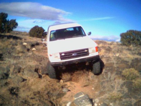 1987 Ford Bronco - This 1987 Ford Bronco navigates a challenging rocky incline under a bright blue sky.