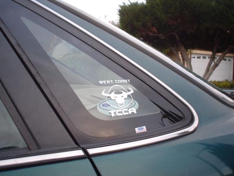 1993 Ford Taurus - A green car's rear window displays a "West Coast TCCA" sticker and a Ford logo sticker.