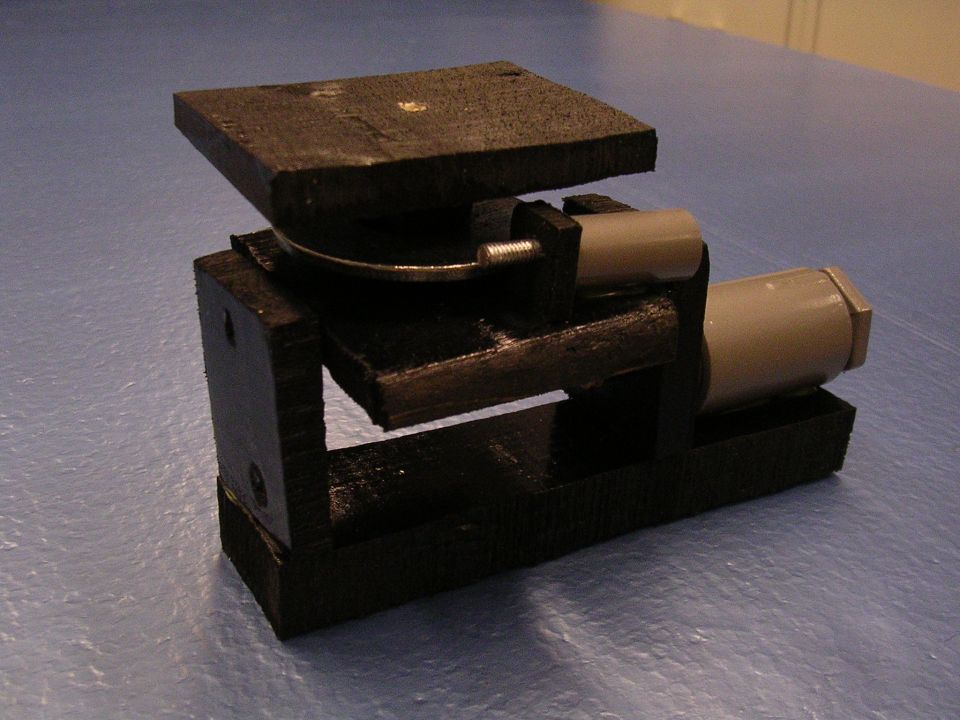 Black homemade mechanical part with a silver disc and gray cylinder