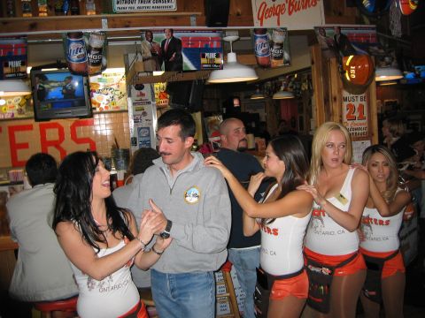 2002 Ford Taurus - People are gathered at a Hooters restaurant, with servers interacting with patrons.
