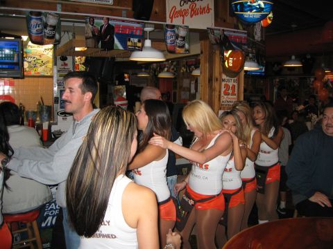 2002 Ford Taurus - A group of people are gathered in a bar, with several waitresses in uniform visible.