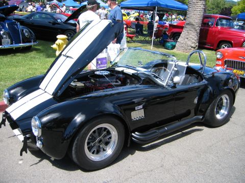 2002 Ford Taurus - A black AC Cobra replica is displayed with its hood open at an outdoor car show.