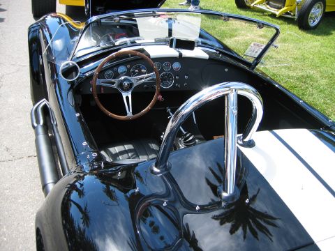 2002 Ford Taurus - Interior view of a black convertible sports car with a wood steering wheel and chrome roll bar, parked outdoors.