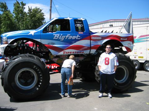 2002 Ford Taurus - A Bigfoot monster truck, painted with a patriotic theme, is shown with two people standing nearby. The registry claims it is a 2002 Ford Ta…