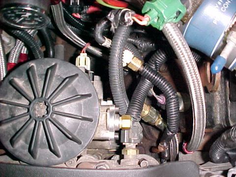 2000 Ford F-250 - Close-up view of engine components including hoses, wiring, and a black fan-like part.