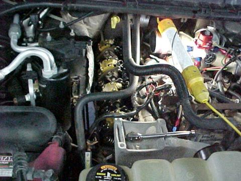 2000 Ford F-250 - Close-up view of an engine bay, showing various hoses, wiring, and a tool.