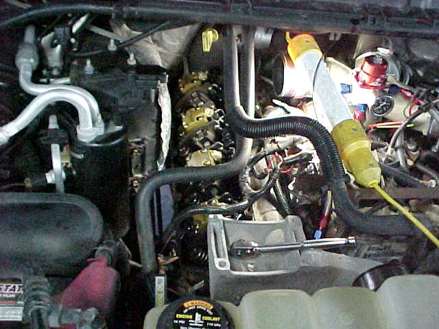 Engine bay with yellow and black hoses, and a ratchet