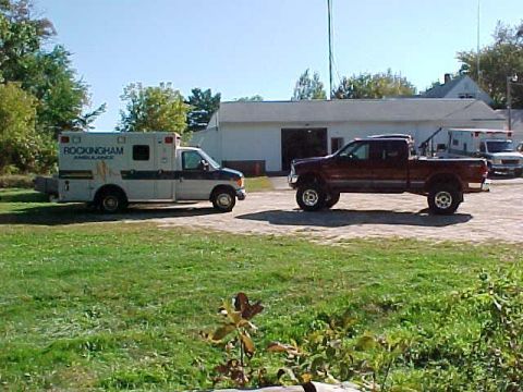 2000 Ford F-250 - A red 2000 Ford F-250 pickup truck is parked next to a Rockingham Ambulance vehicle.