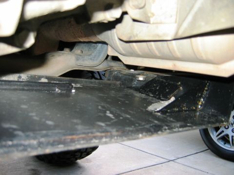 1985 Ford Bronco - Close-up view of the undercarriage, revealing the vehicle's skid plate and exhaust components.