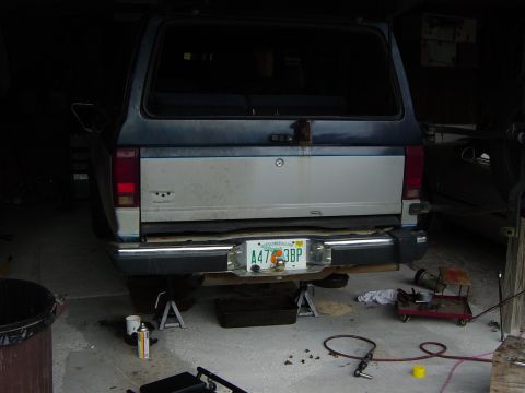1993 Ford Bronco - The rear of a 1993 Ford Bronco is shown in a garage, undergoing maintenance with jack stands supporting the vehicle.