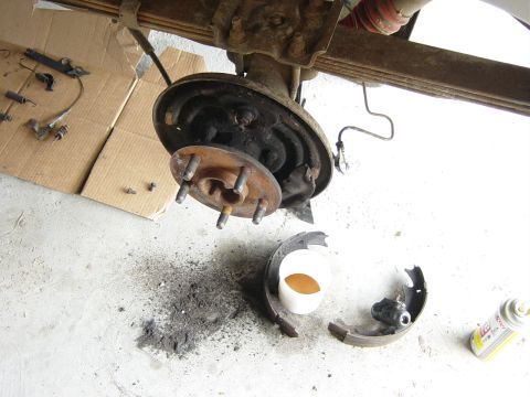 1993 Ford Bronco - A disassembled rear axle brake assembly lies on a concrete surface, with brake dust scattered around.