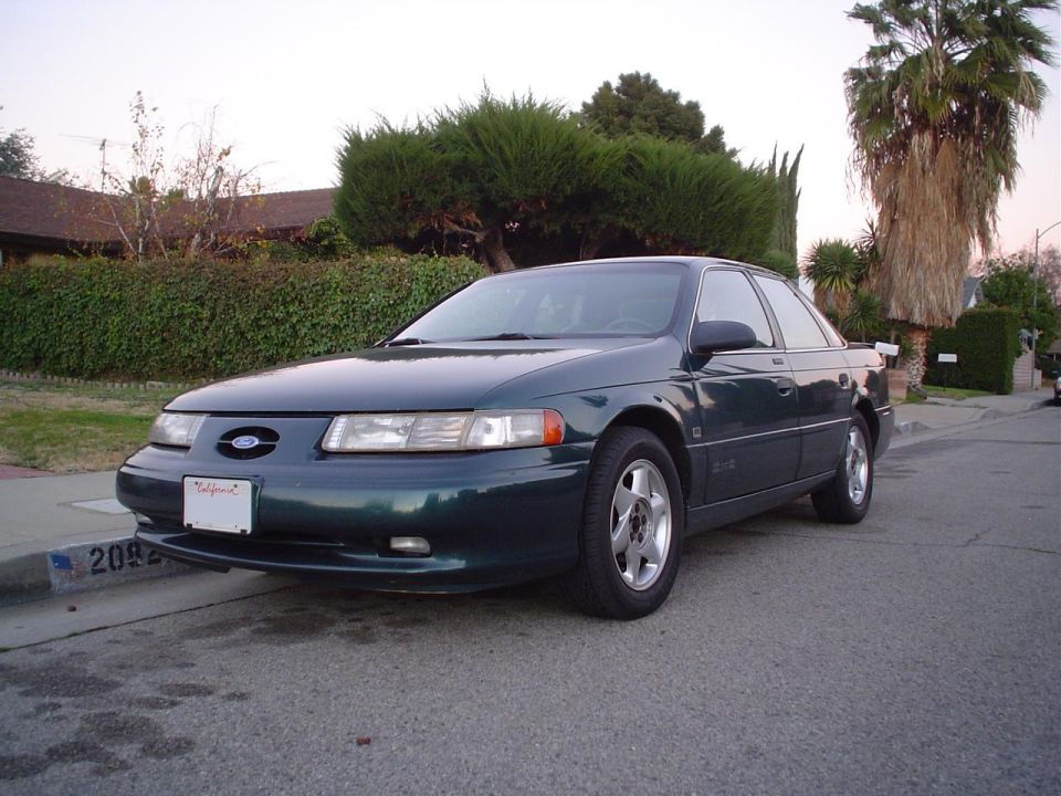 Dark green 1993 Ford Taurus sedan parked on a residential street, front 3/4 view