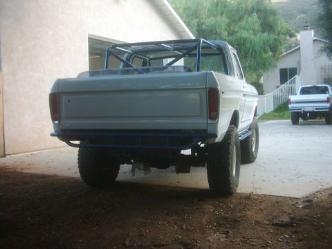 1978 Ford Bronco - This lifted Bronco has a custom roll cage and aftermarket rear bumper, with another truck visible in the background.