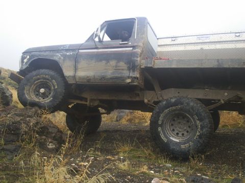1978 Ford Bronco - This flatbed truck, likely from the mid-1970s, is navigating rough, rocky ground.