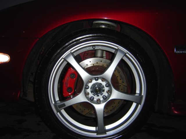 Red car wheel with aftermarket silver rims and red brake calipers