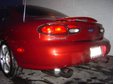 1998 Ford Taurus - Rear view of a red 1998 Ford Taurus showing its taillights, spoiler, and exhaust system.