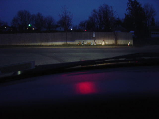 View from inside car at night, dashboard with red glow, headlights on in distance