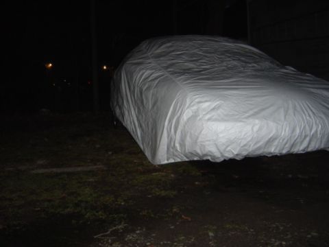 1998 Ford Taurus - Vehicle covered with a white tarp outdoors at night.