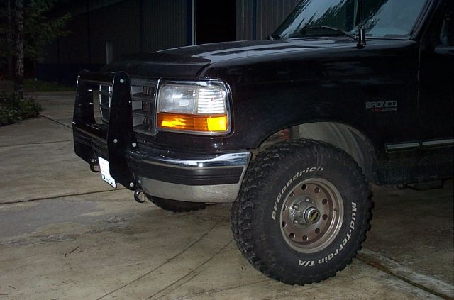 Black Ford Bronco at night, brush guard, BFGoodrich Mud-Terrain tires, headlights on