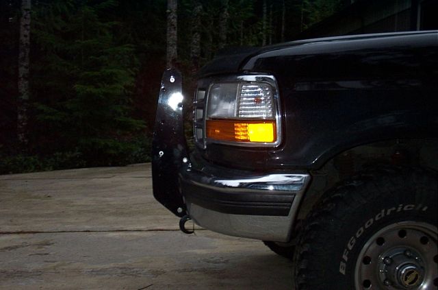 Black Ford front corner at night with lit headlight, chrome bumper, winch plate and BFGoodrich tire