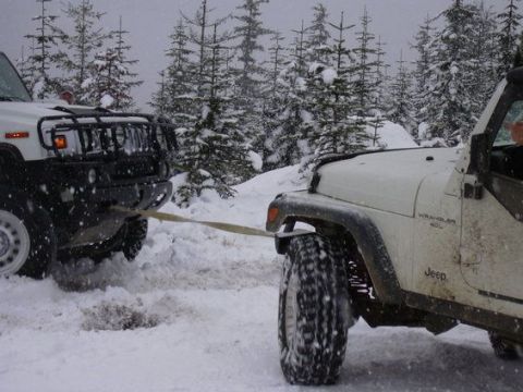 1995 Ford Bronco - A white Jeep Wrangler 4.0L is being towed by a white Hummer through a snow-covered forest during an off-road event.