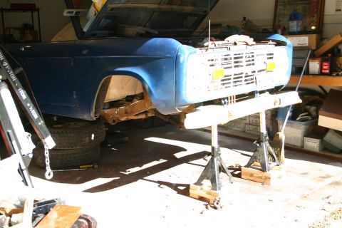 1971 Ford Bronco - This vehicle is undergoing maintenance in a garage, elevated on jack stands with the hood open.