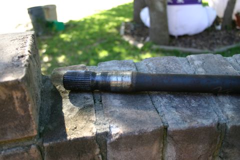 1971 Ford Bronco - A driveshaft part is shown resting on a stone wall outdoors.