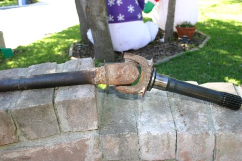 1971 Ford Bronco - A rusty driveshaft with a U-joint is displayed on a stone surface.