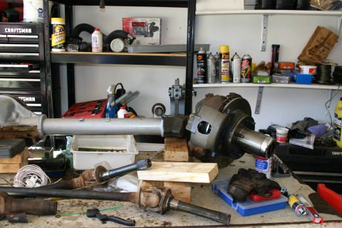 1971 Ford Bronco - Workbench cluttered with automotive differential and axle parts, tools, and supplies.