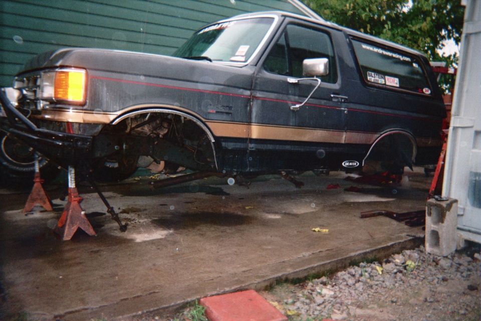 Black Ford Bronco on jack stands with wheels removed in a driveway
