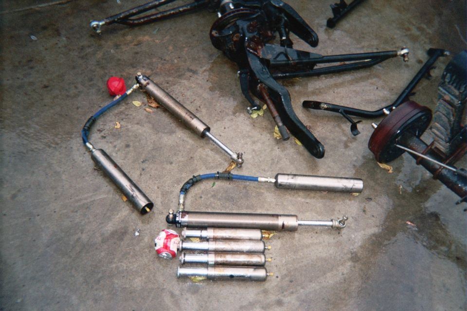 Steering linkage and shock absorbers laid out on a garage floor