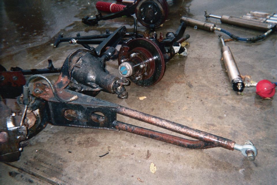 Front axle, radius arm and shocks laid out on a garage floor